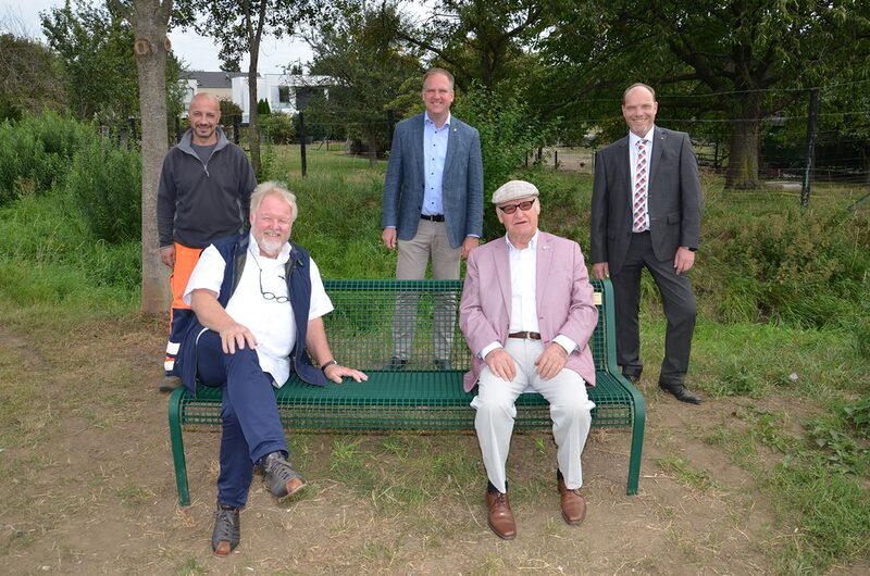 Gioachino Campanella, Otto Winkelhag, Bürgermeister Dirk Breuer, Günter Undorf, Mitglied des Seniorenbeirates, und Stephan Tiefenthal stehen rund um eine Parkbank am Stotzheimer Bach.