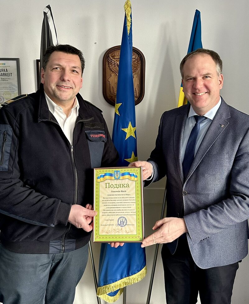 Bürgermeister Dirk Breuer (rechts) überreicht die Urkunde der ukrainischen Feuerwehr stellvertretend an Michael Mund, Leiter der Hürther Feuerwehr.