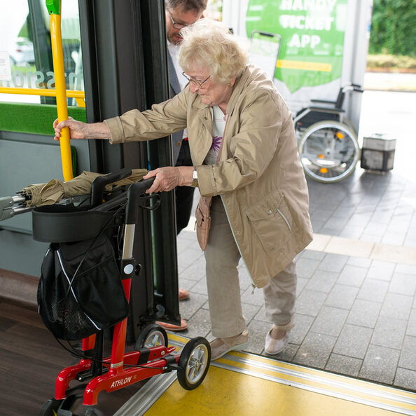 Dame mit Rollator betritt einen Bus.