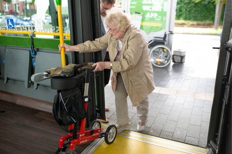 Dame mit Rollator betritt einen Bus.