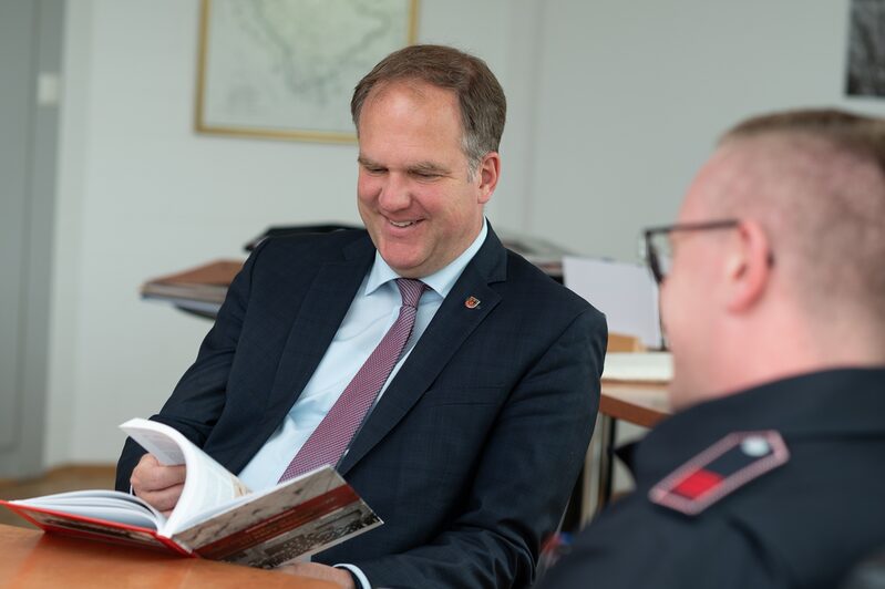 Bürgermeister Dirk Breuer erhält ein druckfrisches Buch zur Geschichte der Freiwilligen Feuerwehr in Hürth.