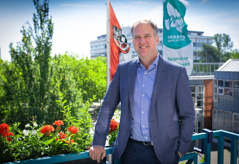 Bürgermeister Dirk Breuer mit der „Mayors for Peace“-Flagge vor dem Rathaus der Stadt Hürth.