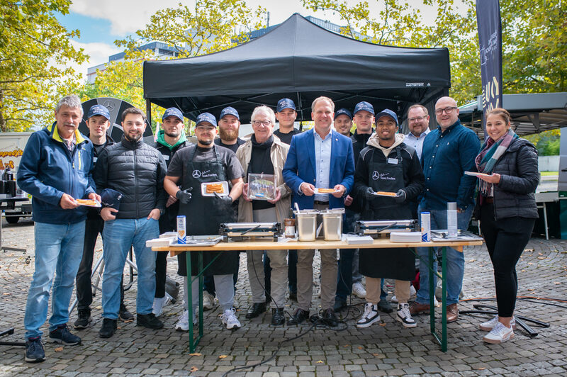 Bürgermeister Dirk Breuer (Mitte) und Rüdiger Winkler vom Partnerschaftsverein Hürth inmitten von Auszubildenden der Daimler Truck AG.