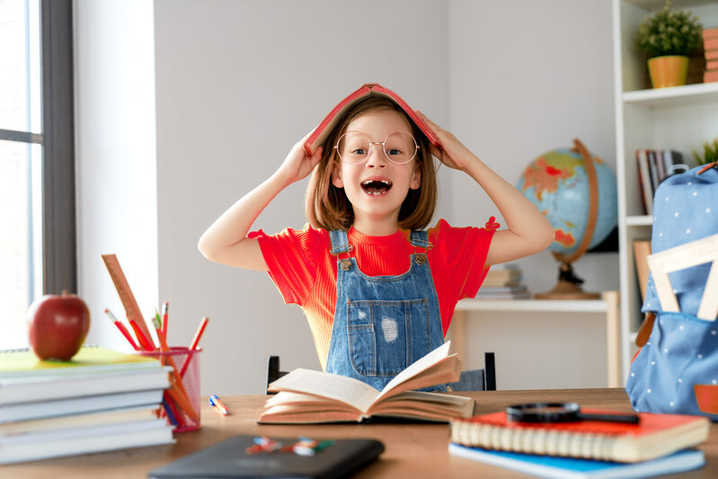 Kind mit Zahnlücke lacht auf der Schulbank