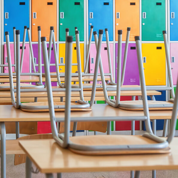 Modern emty classroom with colorful lockers and raised chairs on the tables