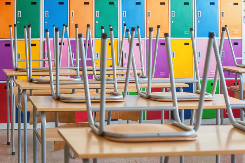 Modern emty classroom with colorful lockers and raised chairs on the tables