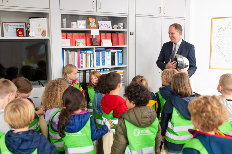 Die Kinder nehmen den Feuerwehrhelm des Bürgermeisters genau unter die Lupe.